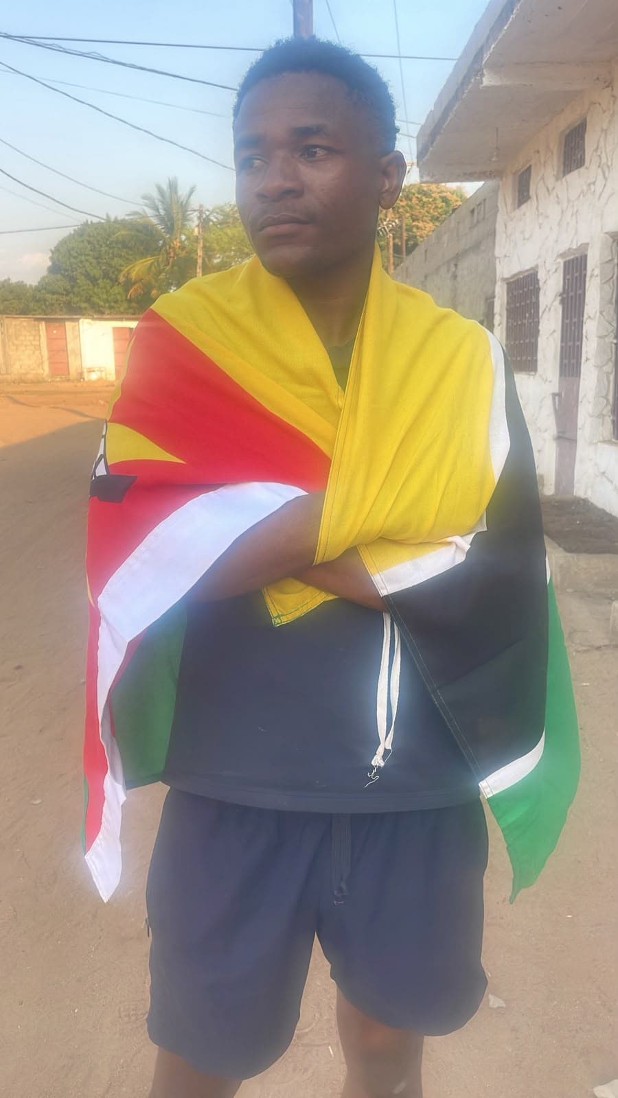Michael numa rua de terra, enrolado na bandeira de Moçambique